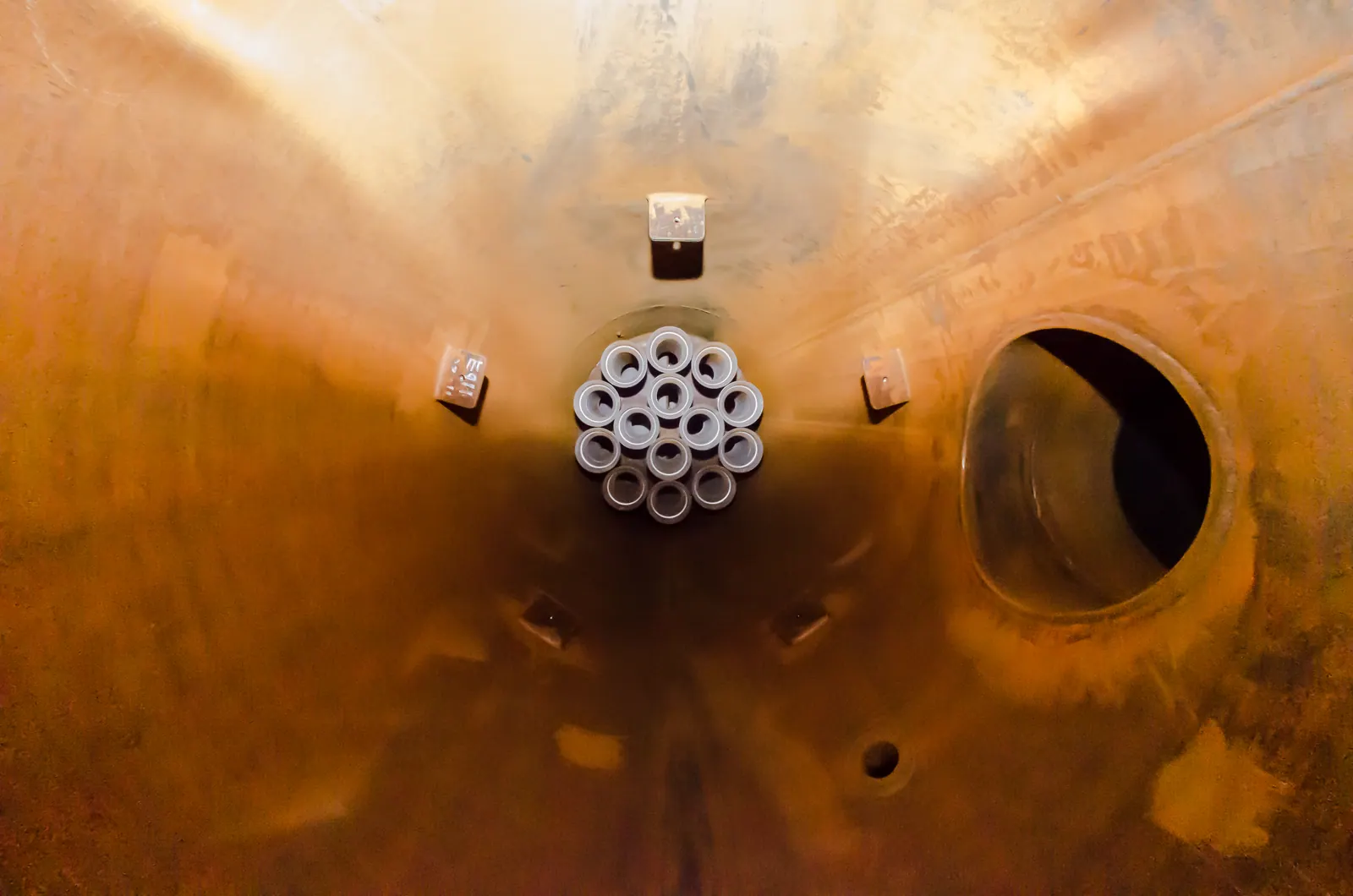 Interior de un recipiente a presión con el haz de tubos y la boca lateral vistos desde el fondo